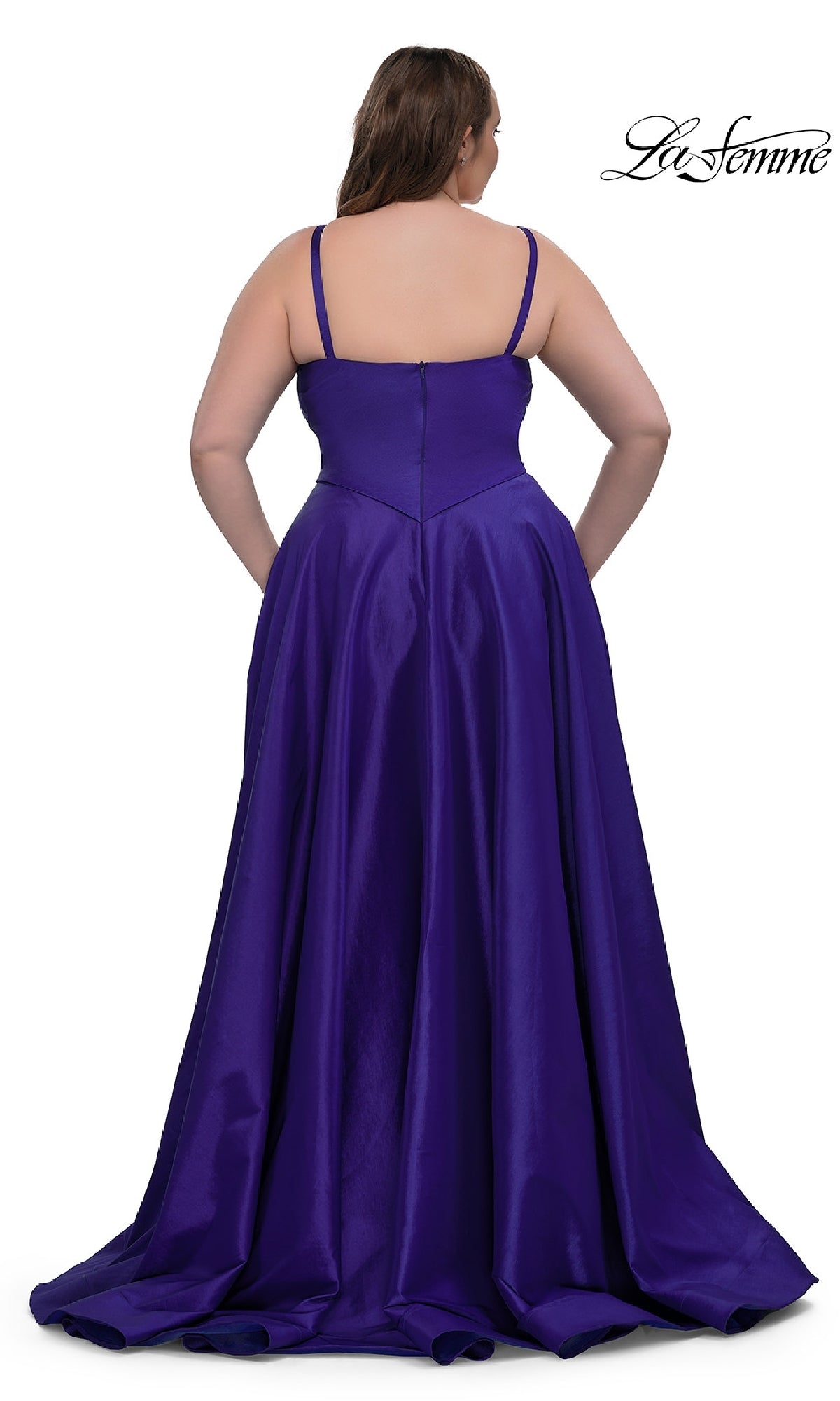 A woman is shown from the back wearing the La Femme 33075, a long plus-size prom dress. The gown features a shiny purple fabric, thin straps, sleeveless bodice, and a full, flowing a-line skirt.
